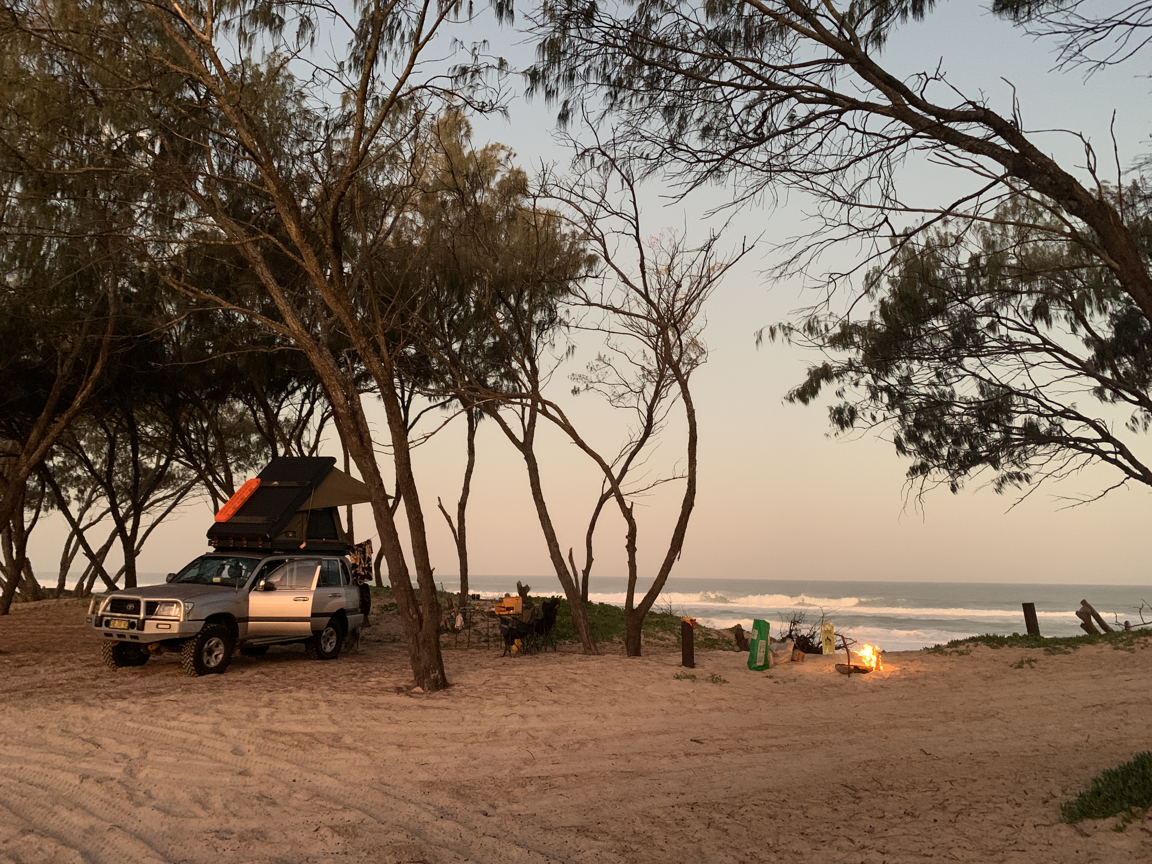 Landcruiser camped on the beach at sunset with campfire